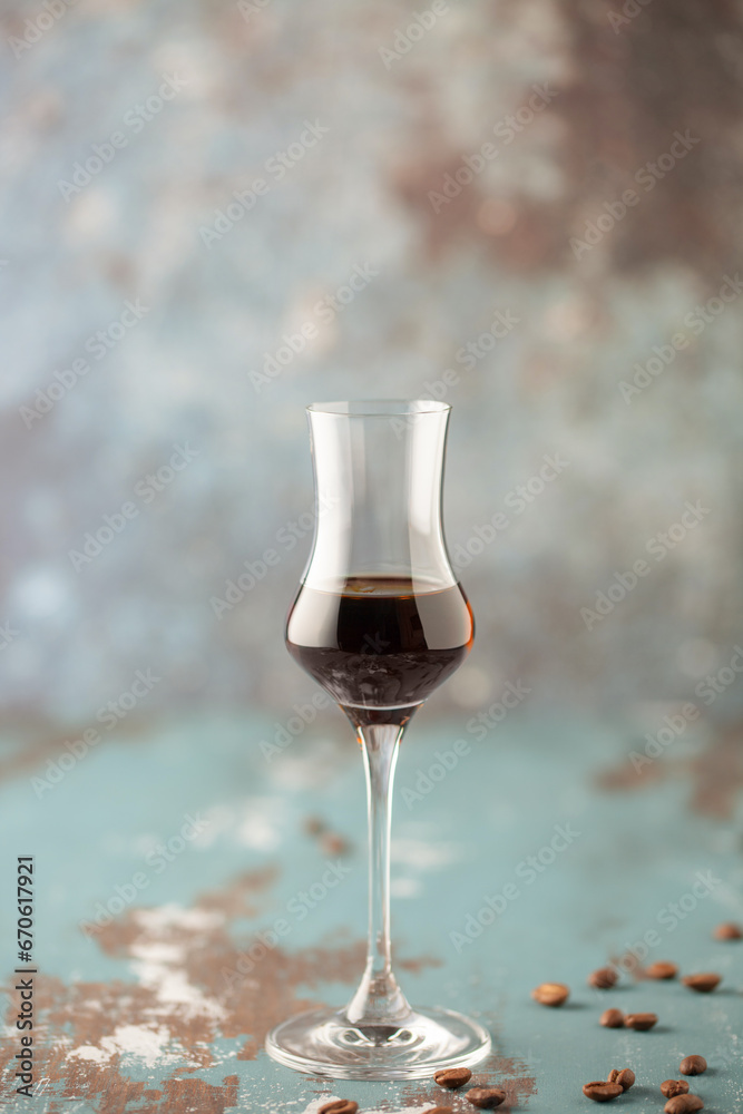 Wall mural Coffee liqueur in  stylish grappa glass and coffee beans on the table