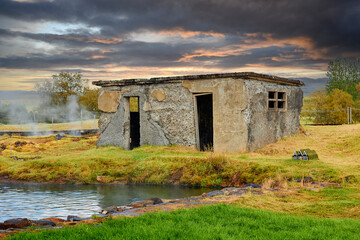 Historical building and ruins reflect on water in rural landscape.