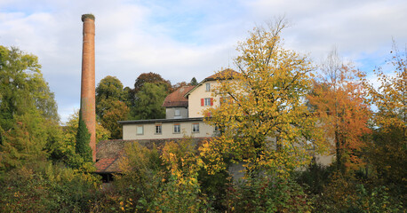 Obraz premium Old factory Schoenau surrounded by colorful trees.