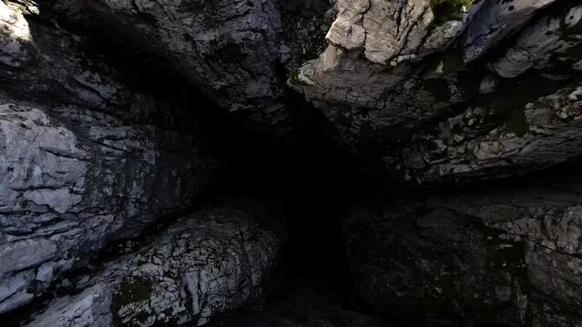 The drone flies out of a bottomless 188 meter pit into a plateau. Nikolina pit. Montenegro. Aerial view.