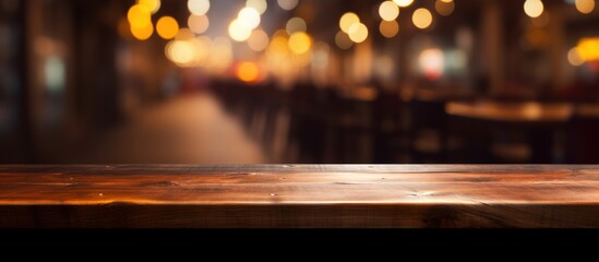 Empty wooden table with a blurred nighttime restaurant backdrop.