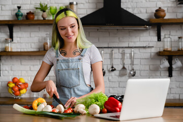 Happy diverse caucasian young teenage girl stylish woman with colorful hair tattoo cooking...