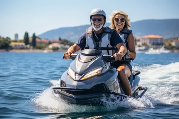 Foto op Canvas Happy senior Caucasian couple in safety helmets and vests riding jet ski on a lake or along sea coast. Active elderly people having fun on water scooter. Healthy lifestyle for retired persons. © Georgii