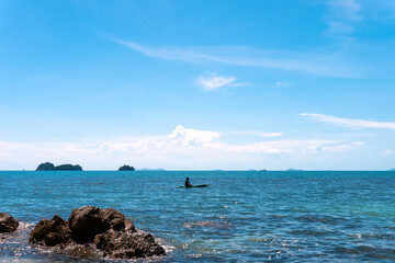 Blue sea wave crashing against rocky stone cliff Islands. Lonely fisherman