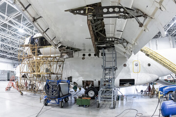 White transport airplane in the aviation hangar. Aircraft under maintenance