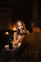 Happy young couple having romantic dinner with candles and red wine at home