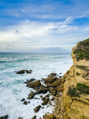 Fototapeta na wymiar Vibrant seascape with a rocky coastline illuminated by sunlight and crashing waves against the shore