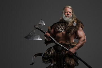 Ancient Viking warrior with gray hair and beard, clad in fur and lightweight armor, wielding a two-handed axe against a neutral backdrop