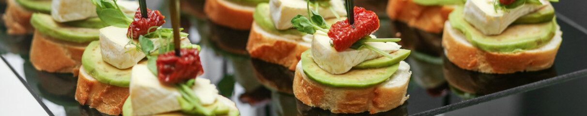 Festive decorated canapes for event with avocado and cheese and dried tomatoes. Banner for web site - obrazy, fototapety, plakaty