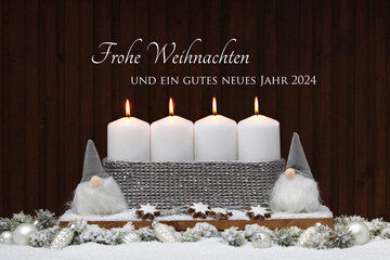 Vier brennende weiße Kerzen mit Weihnachtsdekoration und dem Text Frohe Weihnachten und ein gutes neues Jahr 2024.