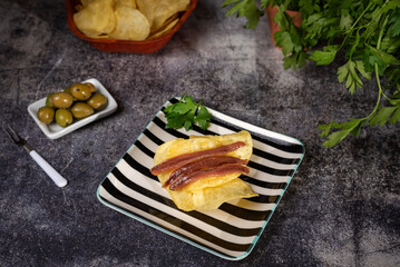 Cantabrian anchovies on chips and accompanied with olives, a typical Spanish tapa.