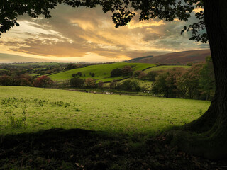 A view across open farm land in Lancashire UK with a low sun in the autumn and the hills behind
