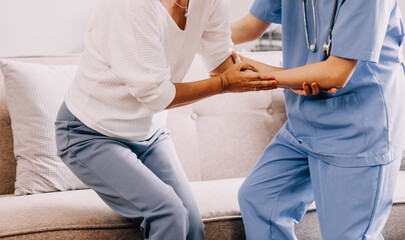 Fototapeta premium Happy young female nurse provide care medical service help support smiling old grandma at homecare medical visit, lady carer doctor give empathy encourage retired patient sit on sofa at home hospital