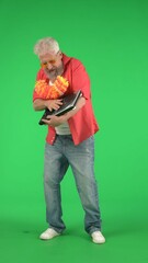 Portrait of senior hipster on Chroma key green screen background, man holding turntable jamming to...