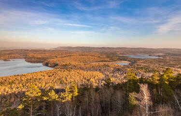 Autumn landscape from the top of a mountain with a lake, trees, mountains and sky