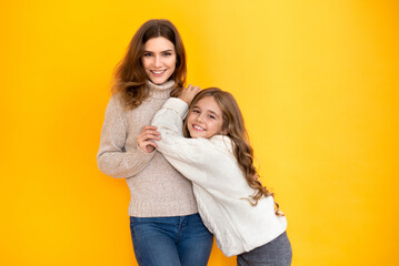 Younger and older sister spending time together on orange background. Sisters having fun and bonding. Background, copy space, close up