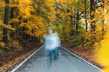 Blurred man in white hoodie, ghost on street with autumn tree foliage