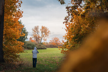 Young man holding his white hoodie and standing in autumn Czech landscape