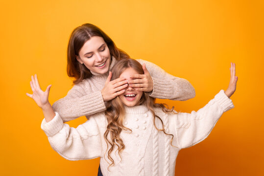 Younger and older sister spending time together on orange background. Sisters having fun and bonding. Background, copy space, close up