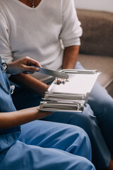 Fototapeta premium Doctor and patient sitting and talking at medical examination at hospital office, close-up. Therapist filling up medication history records. Medicine and healthcare concept.
