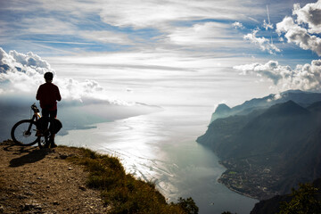 cyclist with mountain bike in the mountains overlooking Lake Garda in Italy - obrazy, fototapety, plakaty