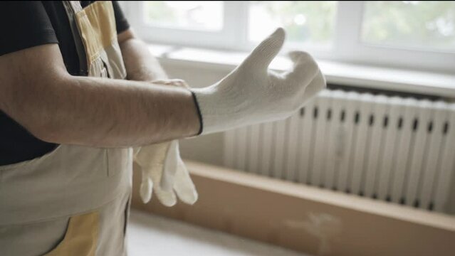 The worker stands in the room and puts on gloves before starting work. Close-up.