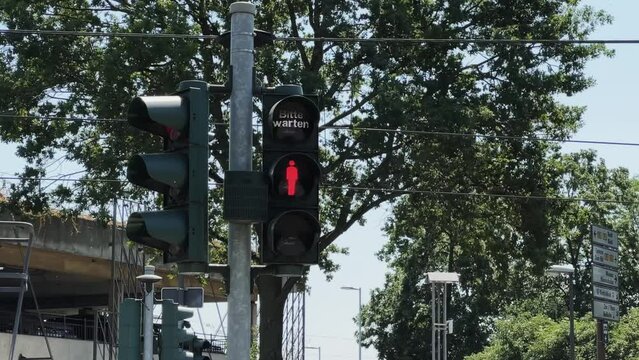 German pedestrian traffic sign changes from red to green on street in Berlin, Germany with warning please wait "bitte warten"