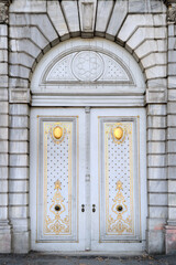 Large wooden door with gold decorative elements.