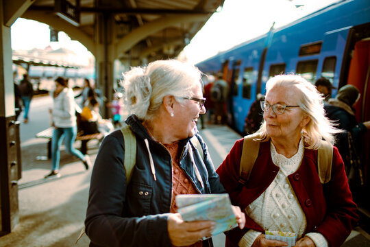 Two elderly friends share a moment at a bustling train station