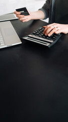 Woman accountant in office, using calculator and holding credit card. Close-up of hands. Online shopping and finance concept. Financial management, digital transactions, business and finance.