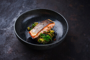 Traditional Japanese gourmet salmon fish steak tataki with chopped avocado, rice and wakame served as close-up on a design bowl with copy space
