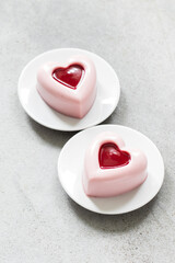Raspberry cream pudding, Panna Cotta in the shape of a heart with raspberry sauce in the center. On a plate. Light gray background. Top view