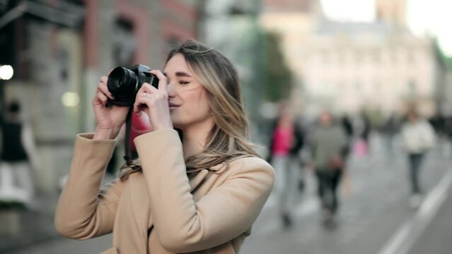 Charming female tourist in stylish wear taking photos during city tour outdoors Pretty young woman enjoying vacation alone