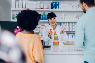 Japanese woman pharmacist selling drugs to a customer in a pharmacy