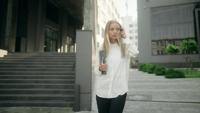 Successful young beautiful blonde woman with tablet walking at office building. Cooperation. Career. Attractive business girl