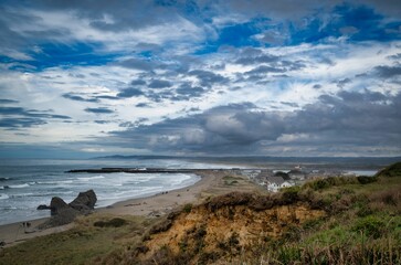 Fototapeta na wymiar Vibrant beach landscape featuring an overcast sky, a tranquil body of water
