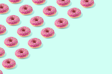 Trendy raw food pattern made with pink doughnut on bright light blue background with copy space. Minima food concept.