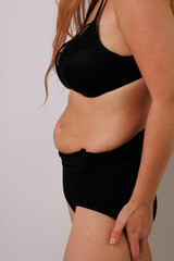 Fototapeta premium Plus size pretty model in correcting figure (body) stretch black shorts. Beautiful lady with big breasts and small waist in underwear to correct her figure. Woman with long hair in bedroom in panties