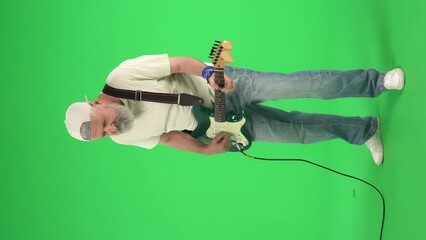Full body portrait of senior hipster on Chroma key green screen, man in white t-shirt playing on electric guitar acts cool. Advertising area, workspace mockup. Vertical video