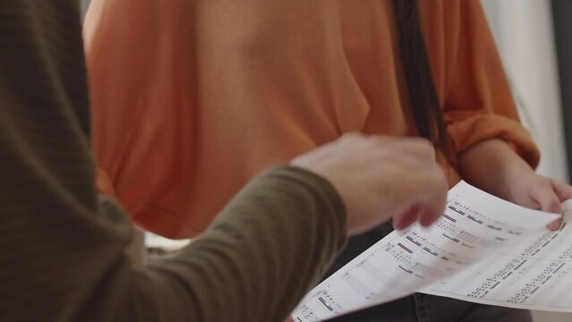 Cropped shot of male and female artists holding sheet music and having conversation at work in home studio