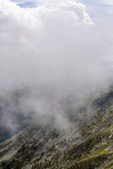 
The mountains, shrouded in a delicate veil of clouds, create an ethereal and mysterious landscape.