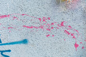 Messy paint strokes and smudges on an old grungy wall. Pink, purple, blue color drips, flows, streaks of paint and paint sprays