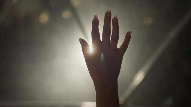 Woman palm silhouette at backlight in dark room closeup