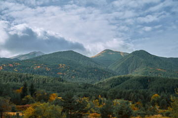 View of the Pirin Mountains on an autumn day, the change of seasons and the forest brightly colored in autumn colors. Idea for background or banner about travel and outdoor recreation, copy space