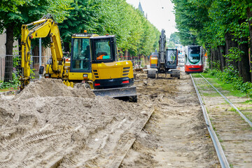 Fototapeta na wymiar Street reconstruction view with several excavators and other machinery, dismantled street surface