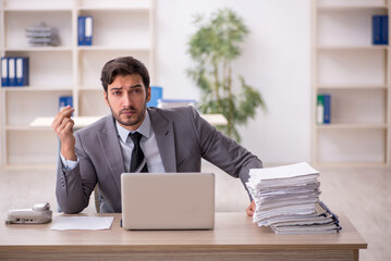 Fototapeta premium Young male employee and too much work in the office