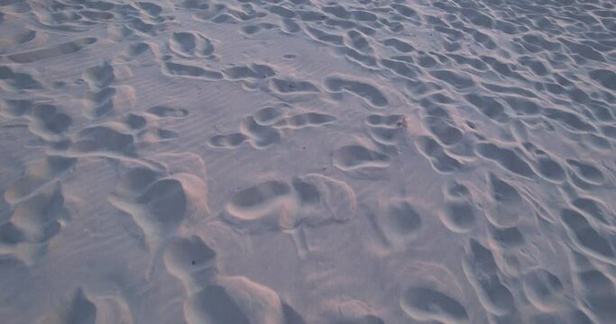 Footprints in the white sand. Sandy beach by the sea at sunset. Trampled sand on the beach