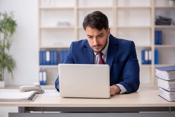 Young male employee sitting at workplace