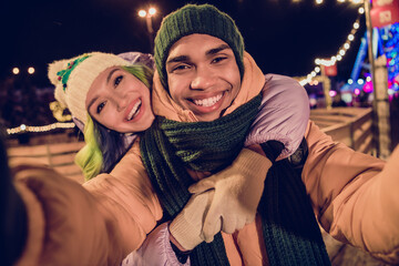 Photo of excited funky american guy lady wear windbreakers blogging recording xmas video vlog together outside urban market park