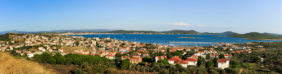Panoramic view of Cunda Island showcasing terracotta-roofed houses, lush greenery, and the sparkling Aegean Sea.  - obrazy, fototapety, plakaty